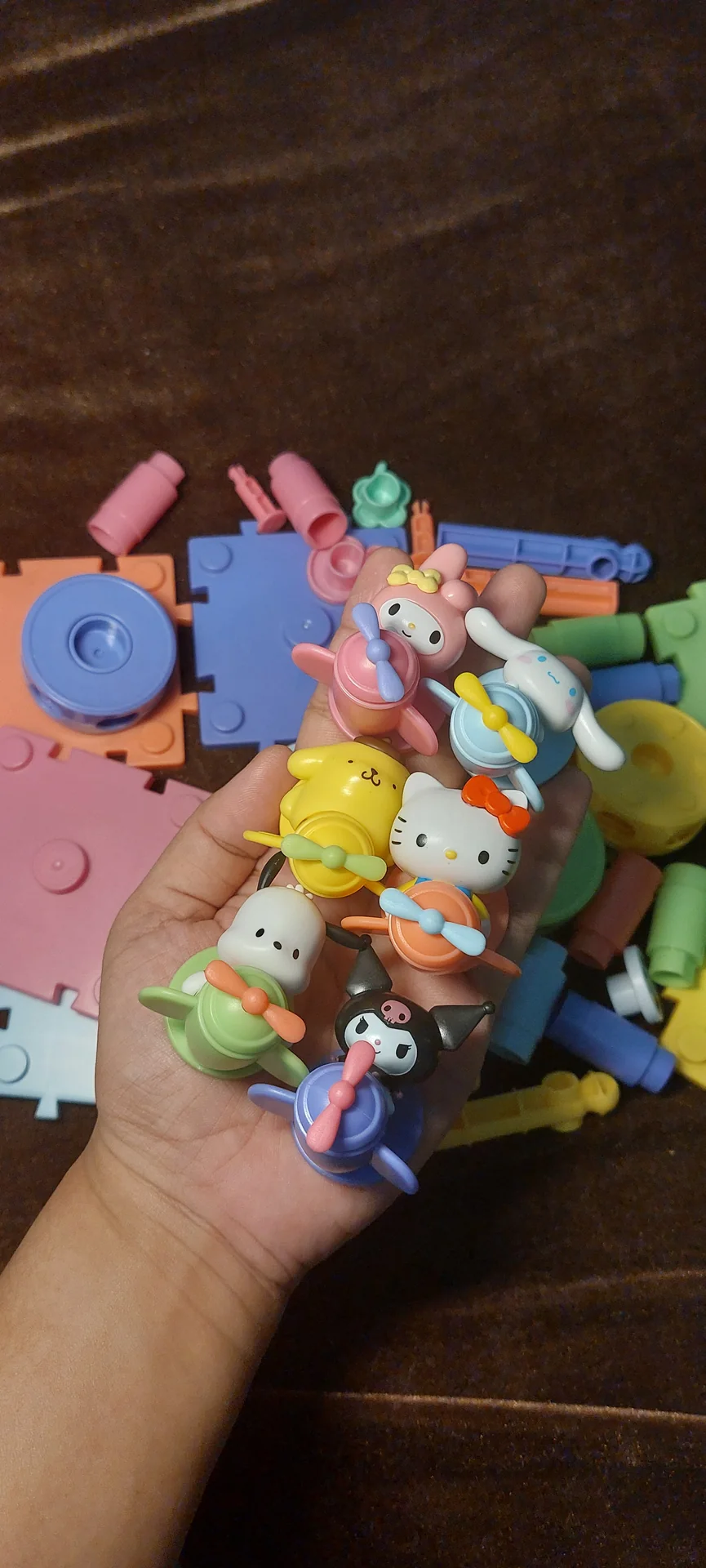 A handful of Sanrio character keychains, Cinnamoroll, My Melody, Hello Kitty, Pompompurin, Kuromi, and a Chococat, cradled in hand