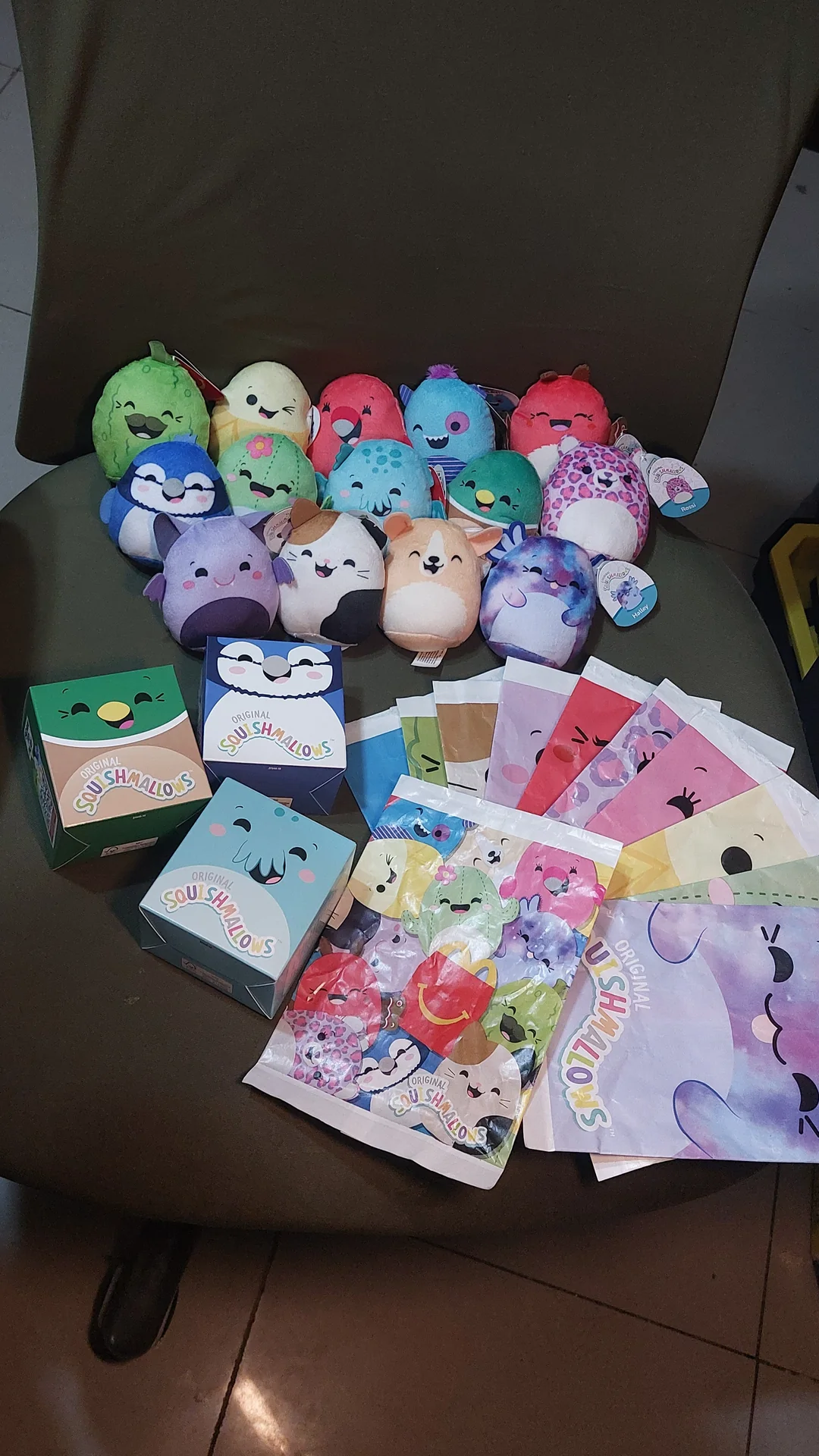 A haul of mini Squishmallow plush figures with their boxes and blind bags spread out on a chair