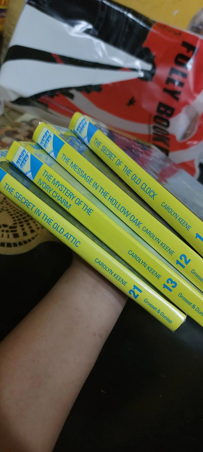 The first four Nancy Drew spines on a shelf: The Secret of the Old Clock, The Message in the Hollow Oak, The Mystery of the Ivory Charm, and The Secret in the Old Attic