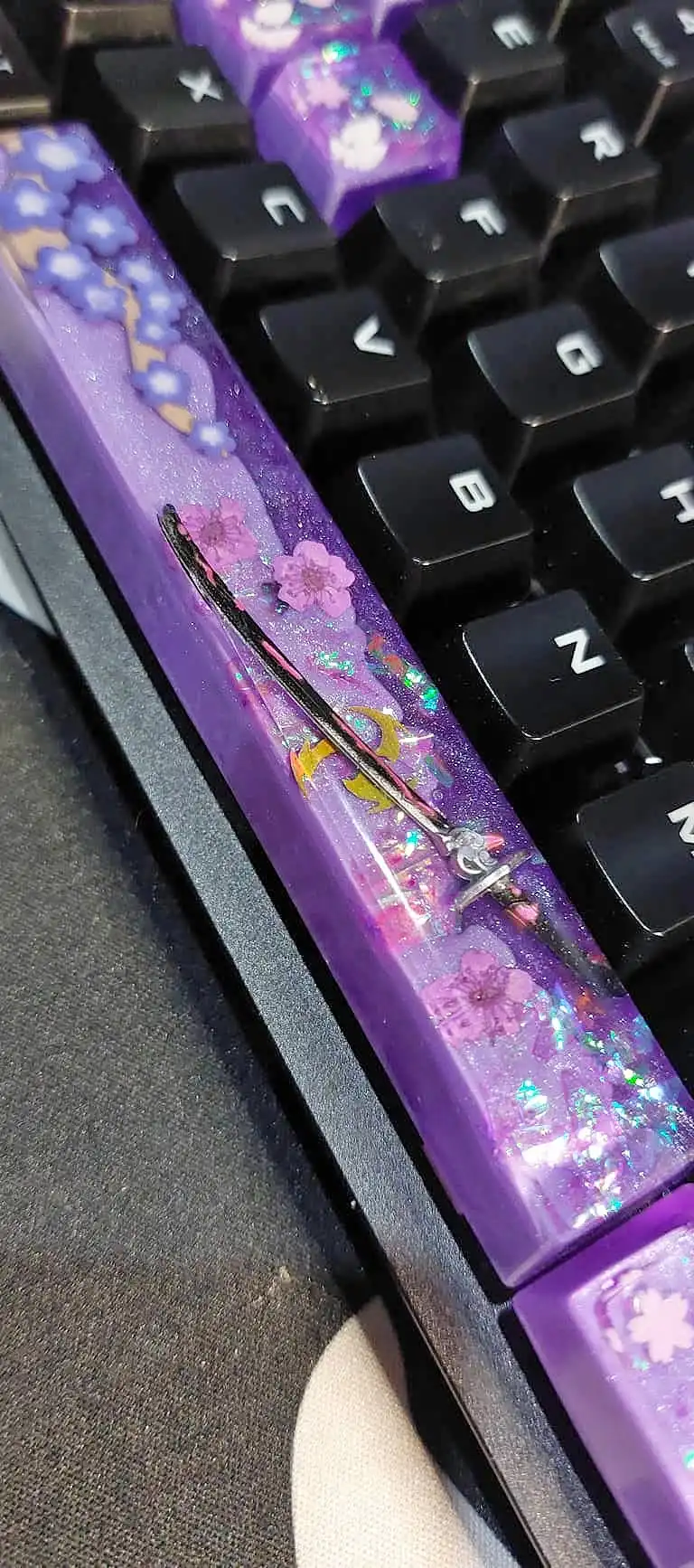 A purple sakura-themed resin keycap on the keyboard, close up